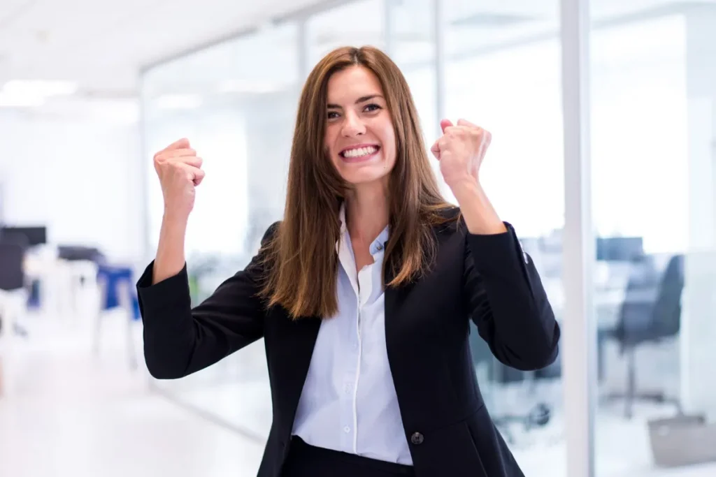 Mulher comemorando uma conquista no escritório, representando a importância de uma mentalidade de crescimento nas empresas.