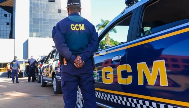 Imagem de agentes da Guarda Municipal de Goiânia (GCM) ao lado de viaturas da corporação, com destaque para o logo GCM nas fardas e carros.