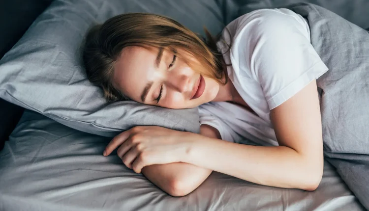 Mulher dormindo tranquilamente em uma cama cinza, representando o processo de lembrança dos sonhos