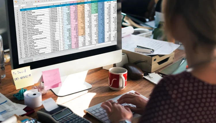 Pessoa trabalhando em uma planilha de Excel no computador, com cálculos financeiros visíveis