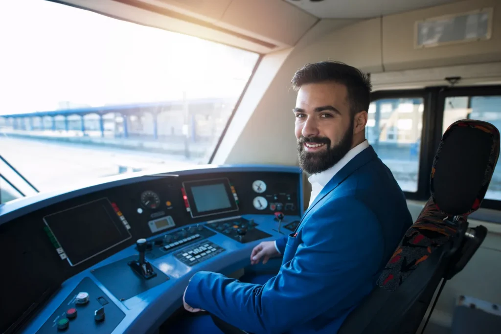 Homem sorridente dentro da cabine de um trem, representando a profissão de piloto