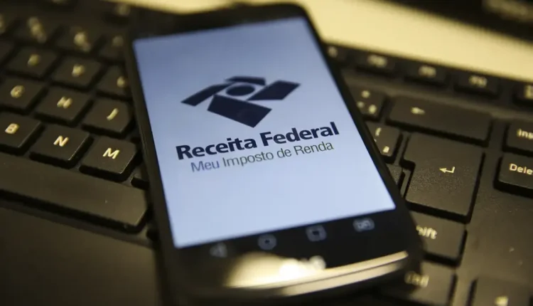 Tela de smartphone exibindo o logo da Receita Federal e o aplicativo "Meu Imposto de Renda", simbolizando a consulta ao lote residual de restituição do IR.