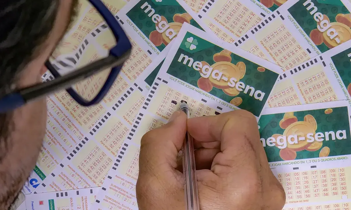 essoa marcando os números na ficha da Mega-Sena, com foco nos bilhetes.